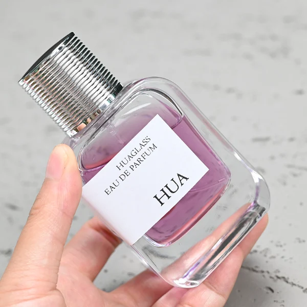HUA0104 perfume bottle, rounded rectangular glass body with liquid and outer HUA label, cylindrical plastic cap with layered ring texture, modern elegant design, available in 30 ml, 50 ml, and 100 ml.