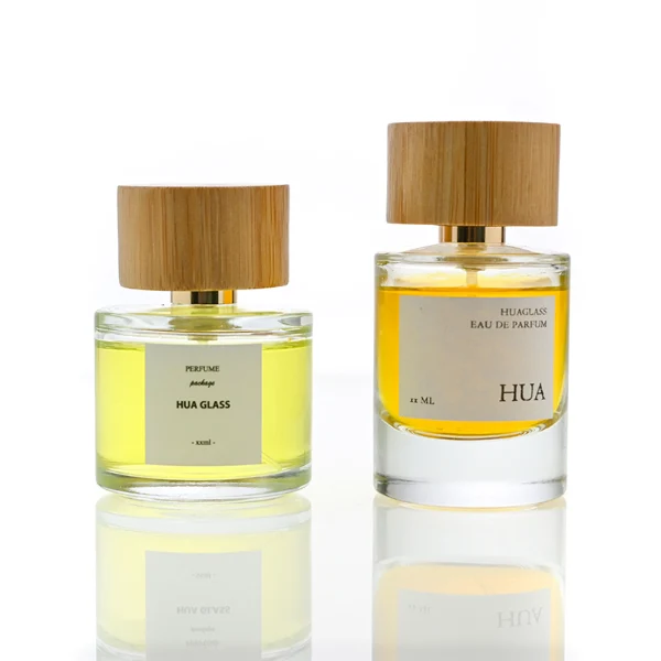 HUA0106 perfume bottle, cylindrical glass body with liquid, wide cylindrical bamboo cap with bright metallic neck, modern minimalist design, available in 30 ml, 50 ml, and 100 ml.