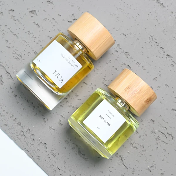 HUA0106 perfume bottle, cylindrical glass body with liquid, wide cylindrical bamboo cap with bright metallic neck, modern minimalist design, available in 30 ml, 50 ml, and 100 ml.
