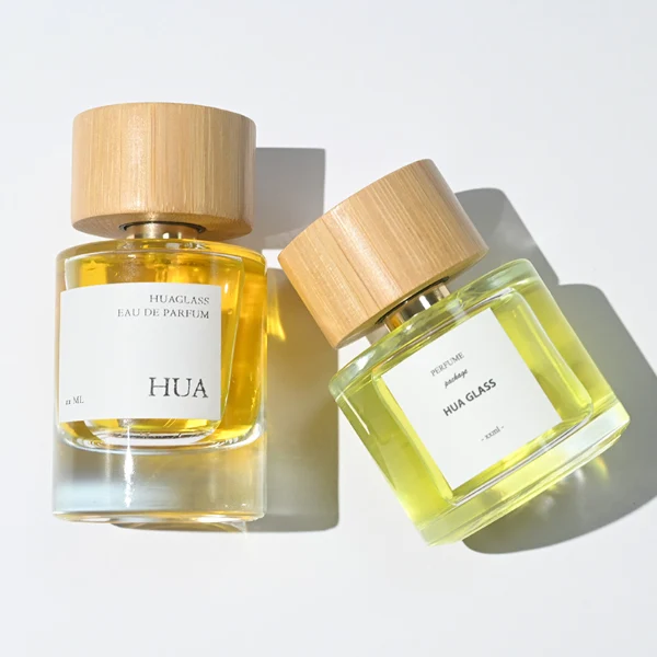 HUA0106 perfume bottle, cylindrical glass body with liquid, wide cylindrical bamboo cap with bright metallic neck, modern minimalist design, available in 30 ml, 50 ml, and 100 ml.