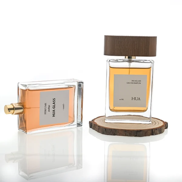 HUA0107 perfume bottle, rectangular glass body with liquid, wide flat wooden cap with metallic-finished neck, modern minimalist design, available in 50 ml and 100 ml.