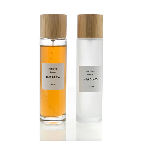 HUA0109 perfume bottle, tall cylindrical glass body with clear and frosted finishes and outer labels, natural bamboo cylindrical cap, modern minimalist design, available in 30 ml, 50 ml, and 100 ml.