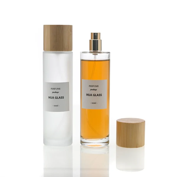 HUA0109 perfume bottle, tall cylindrical glass body with clear and frosted finishes and outer labels, natural bamboo cylindrical cap, modern minimalist design, available in 30 ml, 50 ml, and 100 ml.