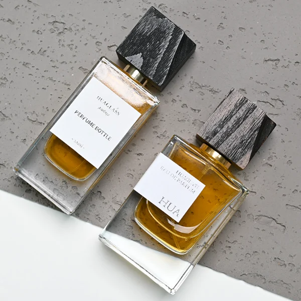 HUA0110 perfume bottle, rectangular glass body with liquid and outer label, black irregular rectangular bamboo cap with gold collar, modern elegant design, available in 50 ml.