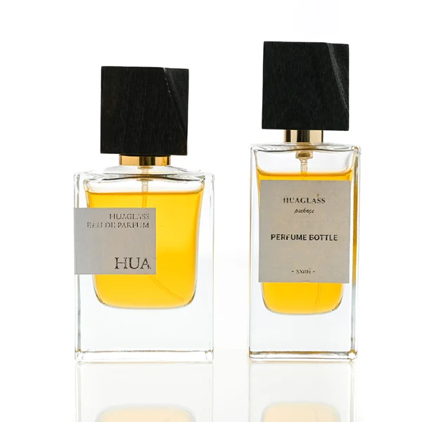 HUA0110 perfume bottle, rectangular glass body with liquid and outer label, black irregular rectangular bamboo cap with gold collar, modern elegant design, available in 50 ml.