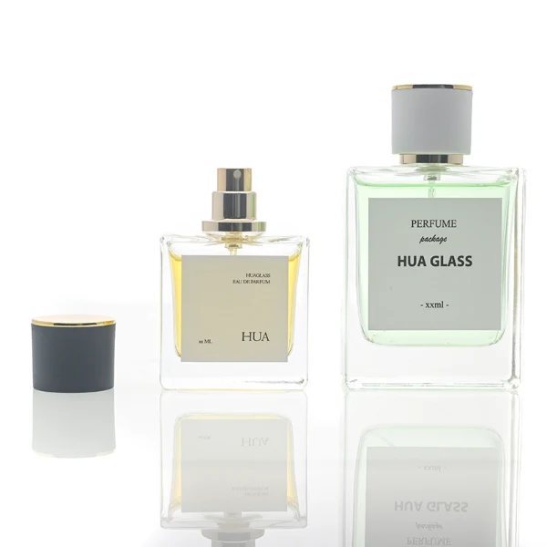 HUA0111 perfume bottle, square glass body with liquid and outer label, cylindrical plastic cap with gold metallic neck, modern minimalist design, available in 30 ml, 50 ml, and 100 ml.