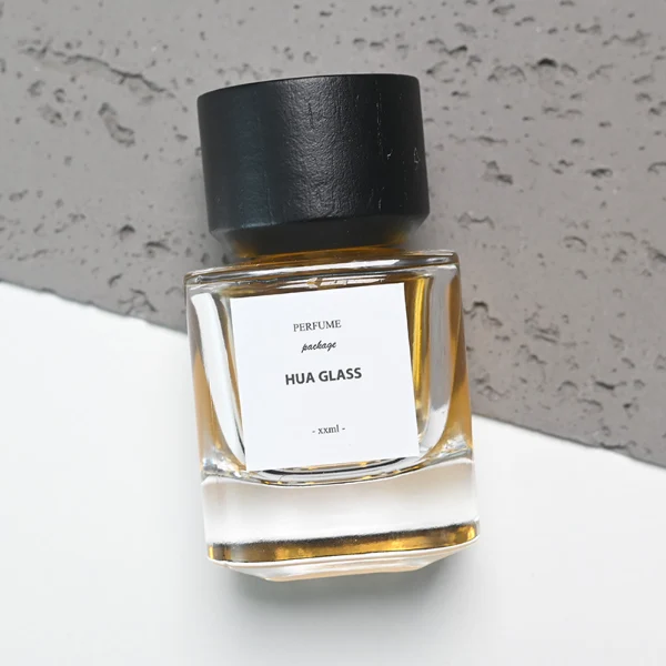 HUA0112 perfume bottle, cylindrical internally sprayed glass with liquid and outer label, wide black wooden cap, modern minimalist design, available in 30 ml, 50 ml, and 100 ml