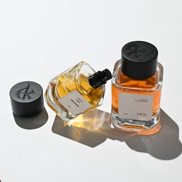 HUA0112 perfume bottle, cylindrical internally sprayed glass with liquid and outer label, wide black wooden cap, modern minimalist design, available in 30 ml, 50 ml, and 100 ml