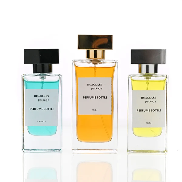 HUA0113 perfume bottle, tall rectangular clear glass body with liquid and outer label, rectangular plastic cap in black or gold, modern elegant design, available in 30 ml, 50 ml, and 100 ml.