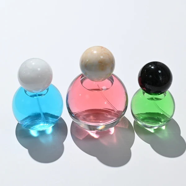 HUA0114 perfume bottle, transparent spherical glass with colorless liquid, resin marble-texture and black ball-shaped caps, label-free modern minimalist design, available in 30 ml, 50 ml, and 100 ml