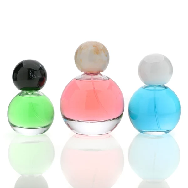 HUA0114 perfume bottle, transparent spherical glass with colorless liquid, resin marble-texture and black ball-shaped caps, label-free modern minimalist design, available in 30 ml, 50 ml, and 100 ml