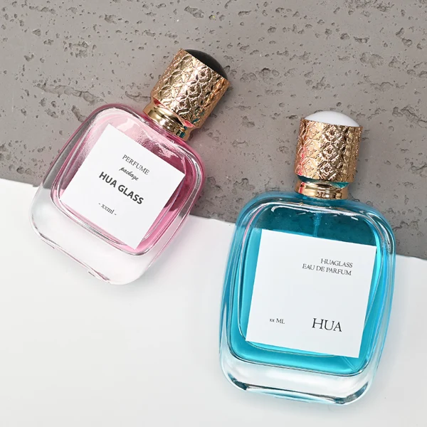 HUA0115 perfume bottle, rounded rectangular glass body with outer label, plastic cap with yellow engraved patterns, modern elegant design, available in 30 ml, 50 ml, and 100 ml.