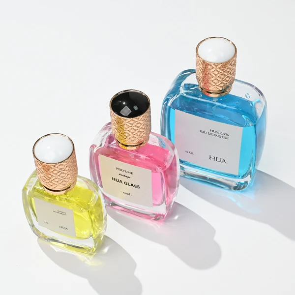 HUA0115 perfume bottle, rounded rectangular glass body with outer label, plastic cap with yellow engraved patterns, modern elegant design, available in 30 ml, 50 ml, and 100 ml.