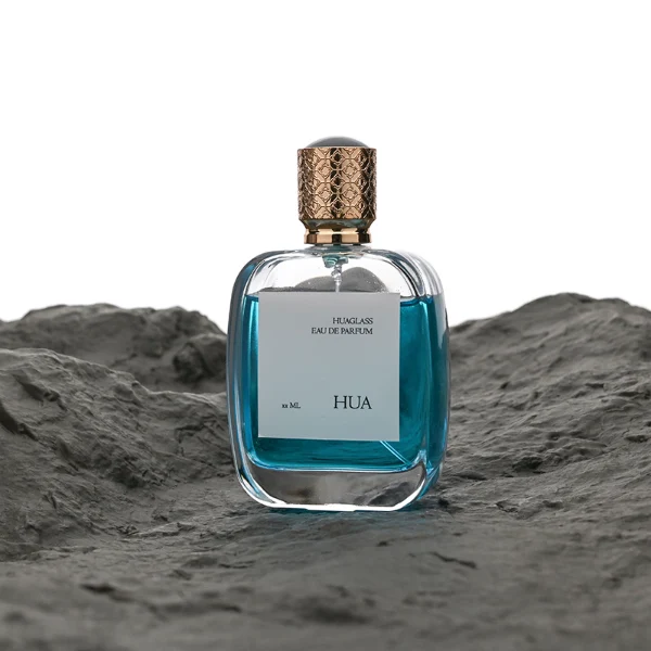 HUA0115 perfume bottle, rounded rectangular glass body with outer label, plastic cap with yellow engraved patterns, modern elegant design, available in 30 ml, 50 ml, and 100 ml.