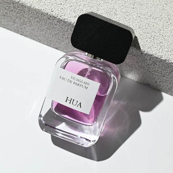 HUA0116 perfume bottle, rounded rectangular glass body with outer label, black rectangular plastic cap with yellow or silver neck accents, modern elegant design, available in 30 ml, 50 ml, and 100 m