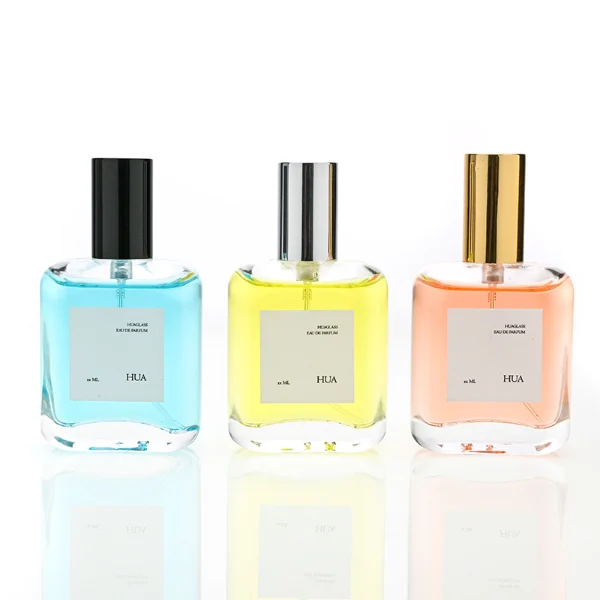 HUA0117 perfume bottle, rounded rectangular clear glass body with outer label, colored aluminum cylindrical cap in black, silver, or gold, modern minimalist design, available in 30 ml.