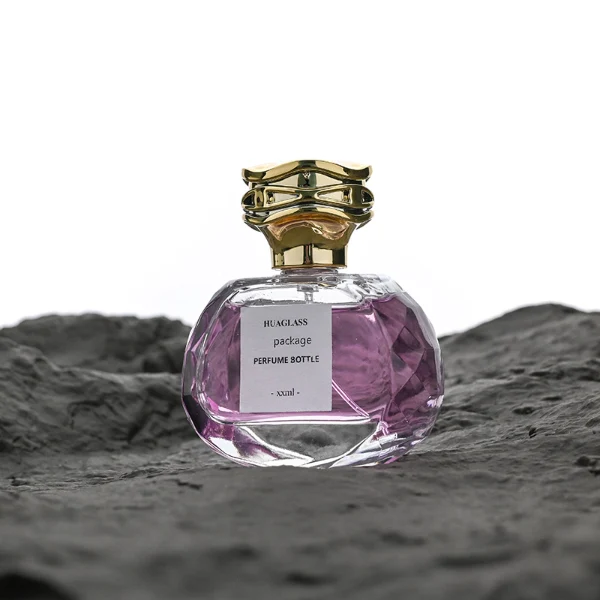 HUA0118 perfume bottle, irregular faceted clear glass body with outer label, plastic irregular-shaped cap with gold metallic neck, modern luxury design, available in 75 ml.