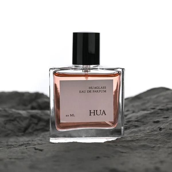 HUA0121 perfume bottle, square clear glass with outer label, aluminum cylindrical cap in black and gold finishes, modern minimalist luxury design, available in 30 ml, 50 ml, and 100 ml