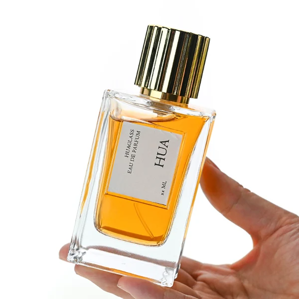 HUA122 perfume bottle, vertically faceted rectangular clear glass body with outer label, striped cylindrical plastic cap in black or gold, modern elegant design, available in 50 ml and 100 ml.