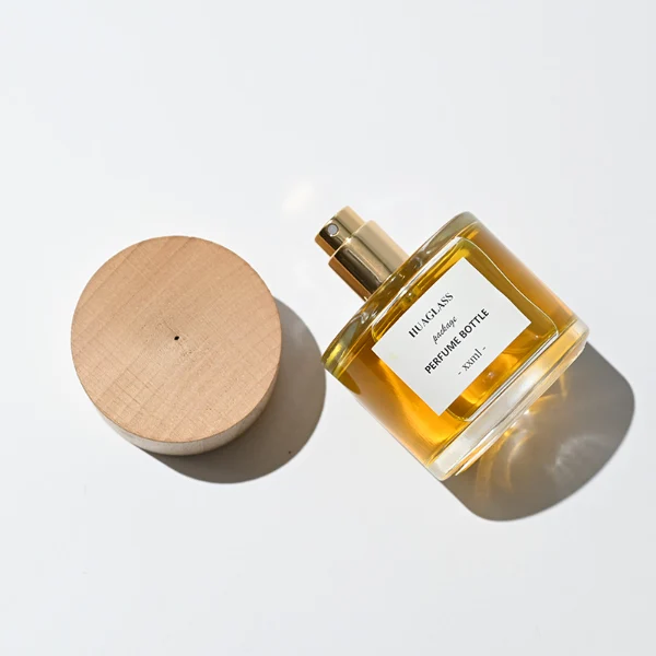 HUA0123 perfume bottle, rounded cylindrical clear glass with outer label, wide wooden cylindrical cap, minimalist modern design, available in 30 ml, 50 ml, and 100 m