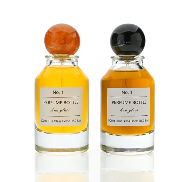 HUA0127 perfume bottle, cylindrical clear glass body with 100 ml liquid, spherical resin cap, outer label with printed logo, modern elegant design, ideal for gifting and daily use.