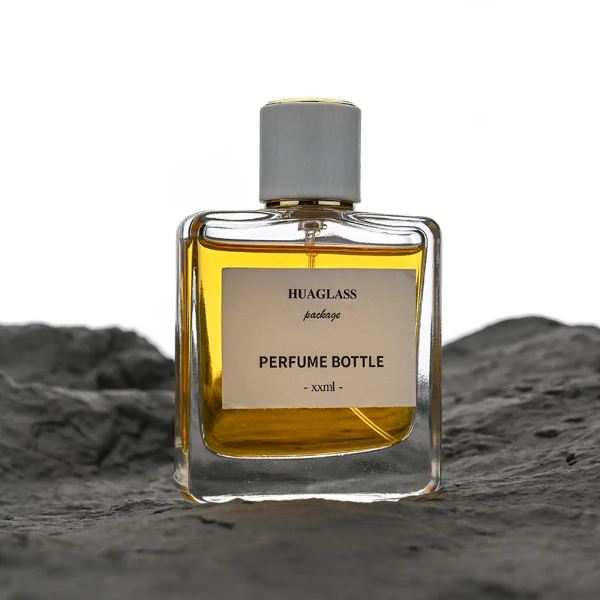 HUA0128 perfume bottle, square clear glass body with 50 ml or 100 ml liquid, cylindrical plastic cap, outer label with printed logo, modern minimalist design, ideal for gifting and daily use.