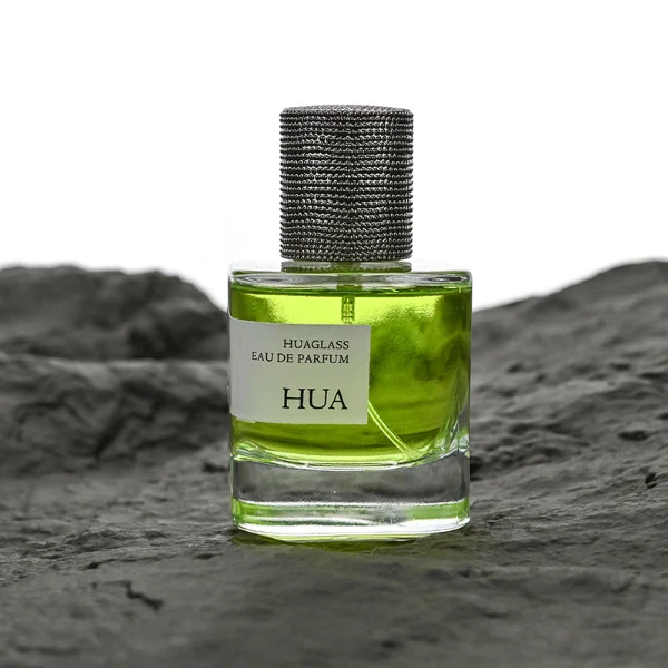 HUA0129 perfume bottle, cylindrical clear glass body with 30 ml, 50 ml, or 100 ml liquid, textured Zamac cylindrical cap, outer label with printed logo, modern elegant design, ideal for gifting and daily use.