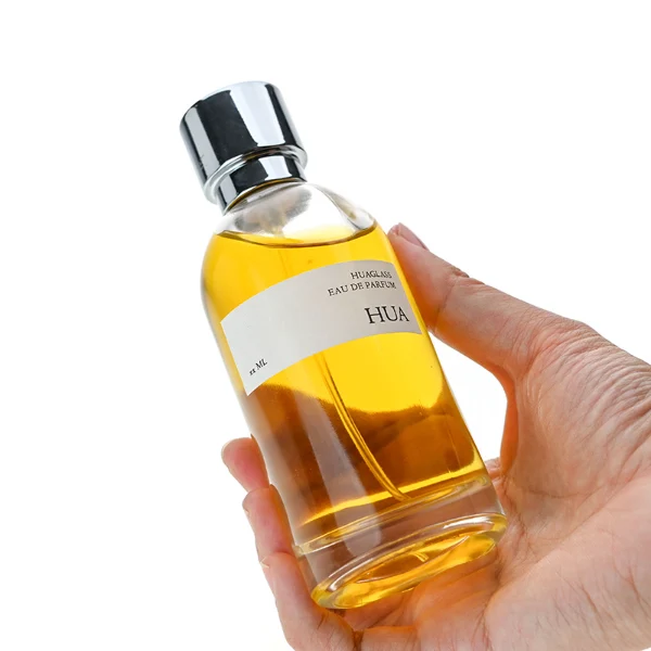 HUA0131 perfume bottle, cylindrical clear glass body with 100 ml liquid, stacked ring-style cylindrical Zamac cap, outer label with printed logo, modern elegant design, ideal for gifting and daily use.