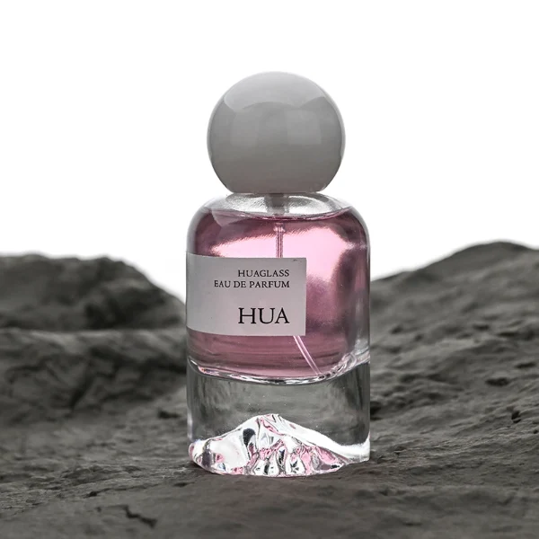 HUA0132 perfume bottle, cylindrical clear glass body with 30 ml, 50 ml, or 100 ml liquid, spherical plastic cap in milky white or black with marble texture, outer label with printed logo, modern minimalist design, ideal for gifting and daily use.