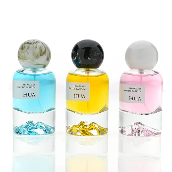 HUA0132 perfume bottle, cylindrical clear glass body with 30 ml, 50 ml, or 100 ml liquid, spherical plastic cap in milky white or black with marble texture, outer label with printed logo, modern minimalist design, ideal for gifting and daily use.