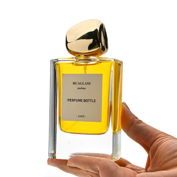 HUA0133 perfume bottle, rectangular clear glass body with 30 ml or 50 ml liquid, irregular-shaped plastic cap, outer label with printed logo, modern elegant design, ideal for gifting and daily use.
