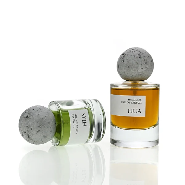 HUA0134 perfume bottle, cylindrical clear glass body with 30 ml, 50 ml, or 100 ml liquid, spherical artificial stone cap, outer label with printed logo, modern minimalist design, ideal for gifting and daily use.