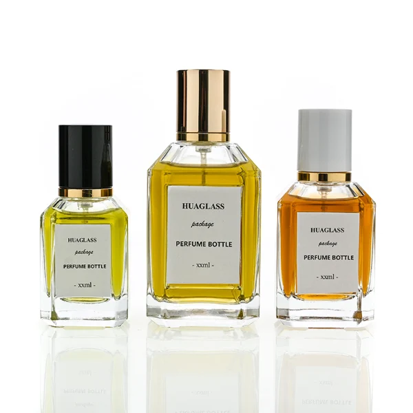 HUA0135 perfume bottle, rectangular clear glass body with 30 ml, 50 ml, or 100 ml liquid, cylindrical plastic cap with gold metallic neck, outer label with printed logo, modern elegant design, ideal for gifting and daily use.