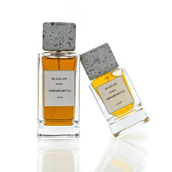 HUA0136 perfume bottle, rectangular clear glass body with 30 ml, 50 ml, or 100 ml liquid, square cement cap, outer label with printed logo, modern minimalist design, ideal for gifting and daily use.