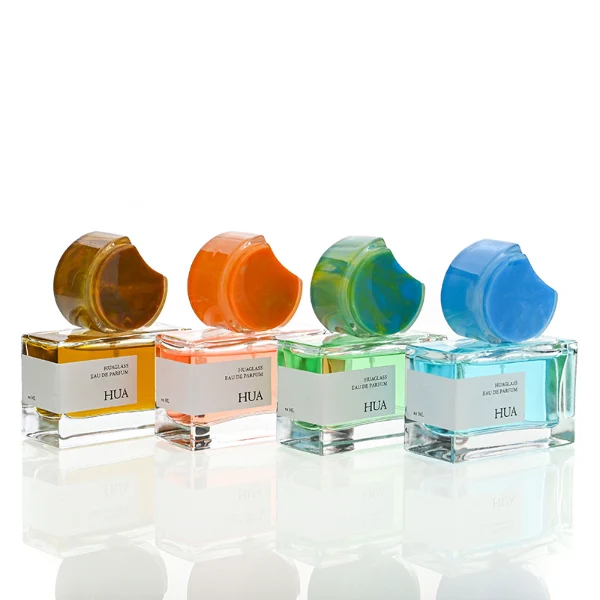 HUA0139 perfume bottle, rectangular clear glass body with 30 ml, 50 ml, or 100 ml liquid, crescent-shaped resin cap with solid marble texture encased in transparent ring, outer label with printed logo, modern elegant design, ideal for gifting and daily use.
