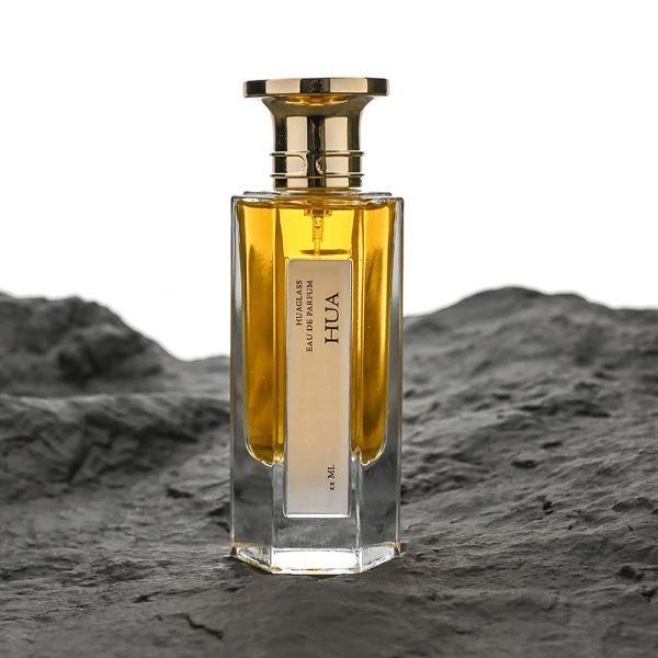HUA0140 perfume bottle, hexagonal clear glass body with 50 ml or 100 ml liquid, Zamac cap with conical funnel top and cylindrical base with ring detailing, outer label with printed logo, modern elegant design, ideal for gifting and daily use.
