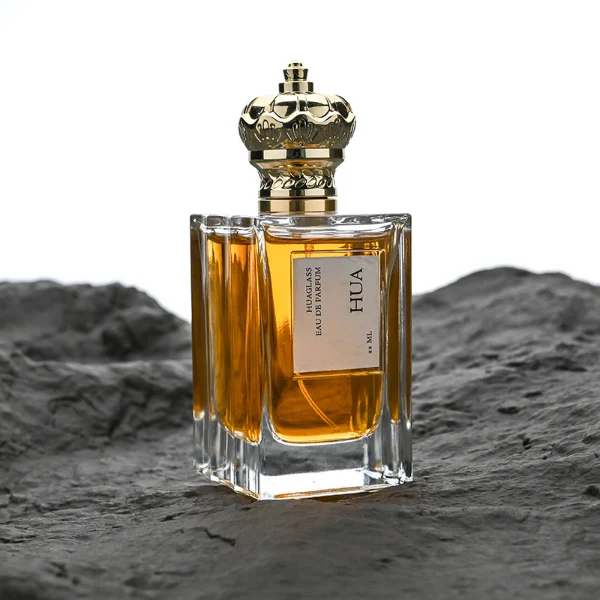 HUA0141 perfume bottle, rectangular clear glass body with 50 ml or 100 ml liquid, crown-shaped plastic cap with gold metallic neck, outer label with printed logo, modern luxurious design, ideal for gifting and daily use.