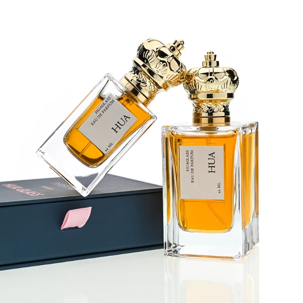 HUA0141 perfume bottle, rectangular clear glass body with 50 ml or 100 ml liquid, crown-shaped plastic cap with gold metallic neck, outer label with printed logo, modern luxurious design, ideal for gifting and daily use.