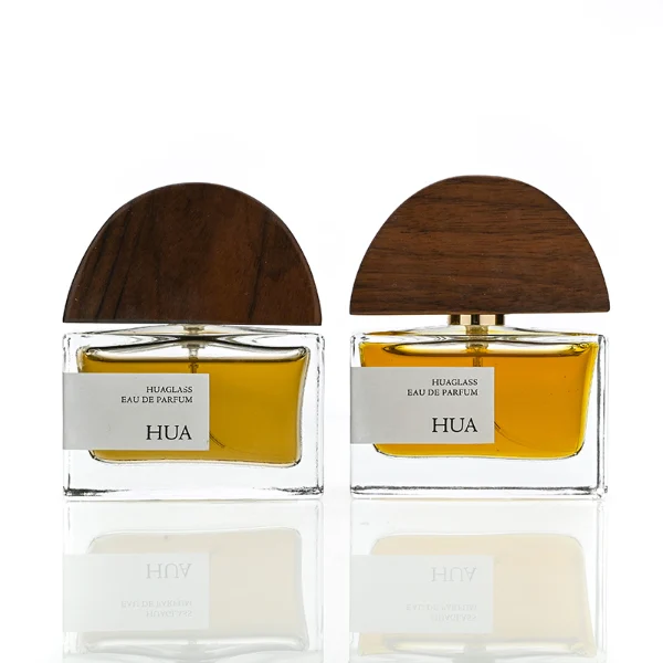HUA0144 perfume bottle, rectangular clear glass body with 30 ml, 50 ml, or 100 ml liquid, half-circle wooden cap with gold metallic neck, outer label with printed logo, modern elegant design, ideal for gifting and daily use.