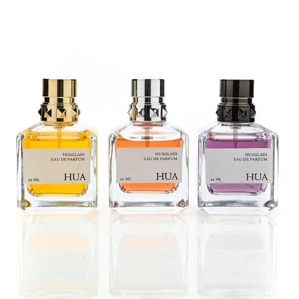 HUA0147 perfume bottle, rectangular clear glass body with 50 ml, 70 ml, or 100 ml liquid, layered ring-shaped plastic cap with diamond-textured base, outer label with printed logo, modern luxurious design, ideal for gifting and daily use.
