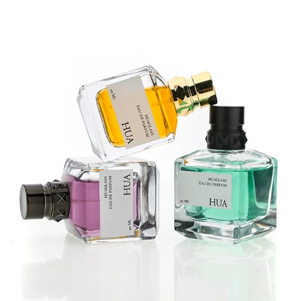 HUA0147 perfume bottle, rectangular clear glass body with 50 ml, 70 ml, or 100 ml liquid, layered ring-shaped plastic cap with diamond-textured base, outer label with printed logo, modern luxurious design, ideal for gifting and daily use.