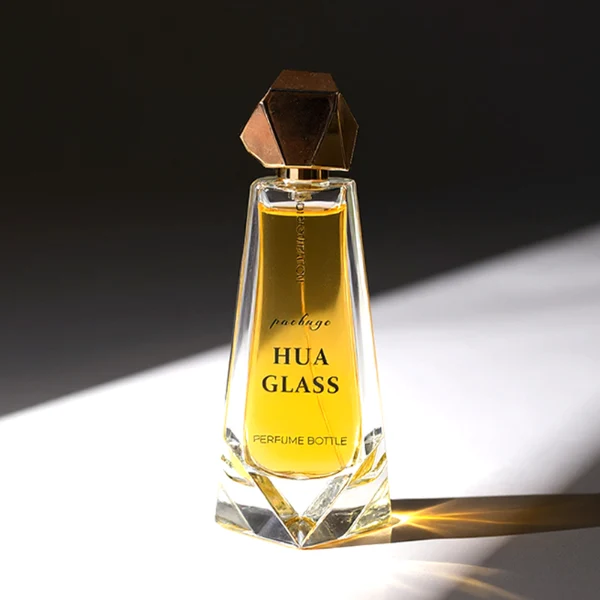 HUA0150 perfume bottle, trapezoidal faceted glass body with 100 ml liquid, irregular multi-faceted plastic cap with plastic neck, outer label with printed logo, modern luxurious design, ideal for gifting and daily use.