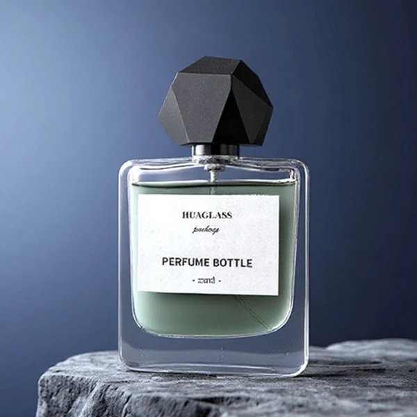 HUA0152 perfume bottle, rectangular clear glass body with 50 ml or 100 ml liquid, faceted geometric plastic cap, outer label with printed logo, modern luxurious design, ideal for gifting and daily use.
