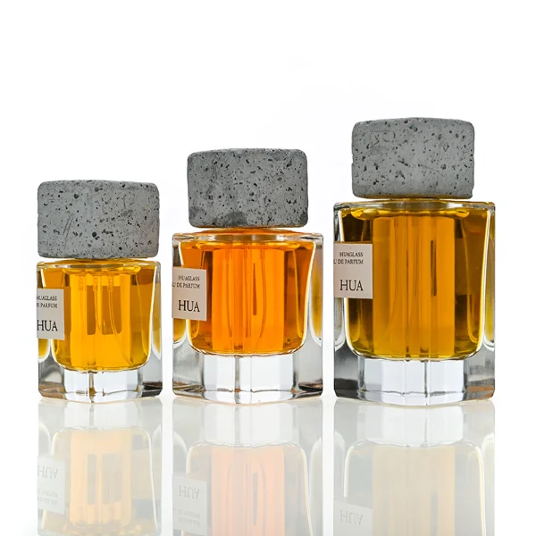 HUA0153 perfume bottle, rectangular clear glass body with 30 ml, 50 ml, or 100 ml liquid, square cement cap, outer label with printed logo, modern elegant design, ideal for gifting and daily use.
