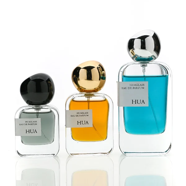 HUA0154 perfume bottle, rectangular clear glass body with 30 ml, 50 ml, or 100 ml liquid, irregular spherical plastic cap with customizable color, outer label with printed logo, modern elegant design, ideal for gifting and daily use.