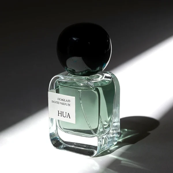 HUA0154 perfume bottle, rectangular clear glass body with 30 ml, 50 ml, or 100 ml liquid, irregular spherical plastic cap with customizable color, outer label with printed logo, modern elegant design, ideal for gifting and daily use.