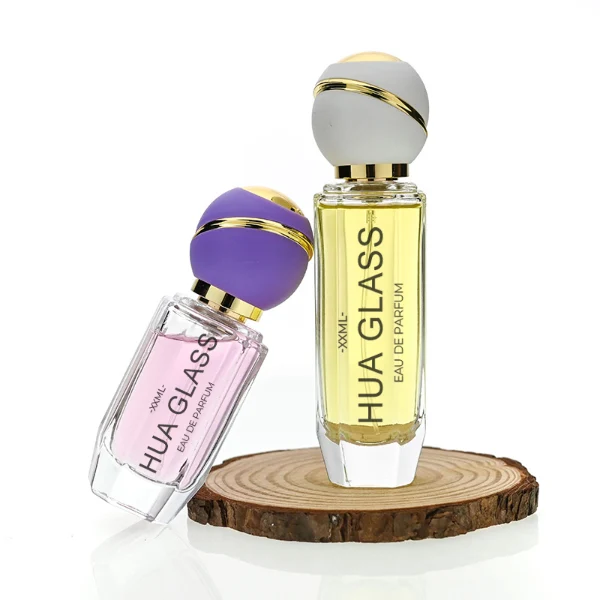 HUA0155 perfume bottle, cylindrical transparent glass body with 30 ml, 50 ml, or 100 ml liquid, spherical plastic cap with diagonal gold stripe, gold top, and gold metallic neck, outer label with printed logo, modern elegant design, ideal for gifting and daily use.