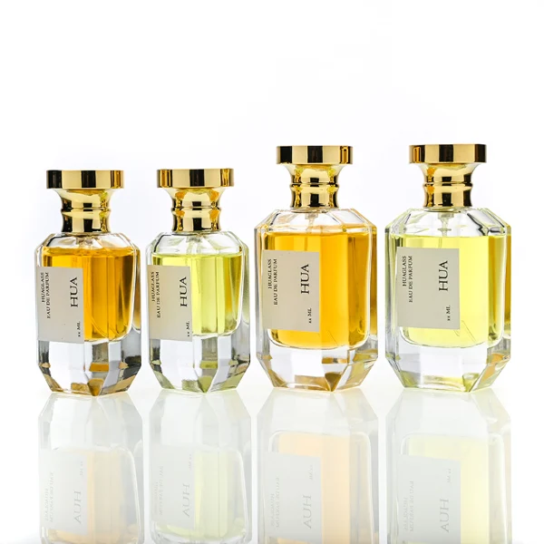 HUA0156 perfume bottle, multifaceted clear glass body with 30 ml, 50 ml, or 100 ml liquid, cylindrical cap with flat top and stepped base in gold, outer label with printed logo, modern elegant design, ideal for gifting and daily use.