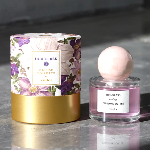 HUA0157 perfume bottle, cylindrical clear glass body with 30 ml, 50 ml, or 100 ml liquid, spherical crystal stone cap, outer label with printed logo, modern elegant design, ideal for gifting and daily use.