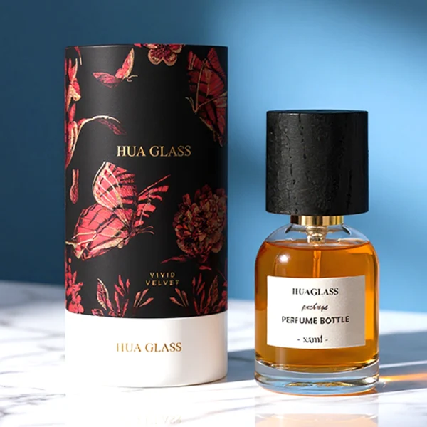 HUA0162 perfume bottle, cylindrical transparent glass body with 30 ml, 50 ml, or 100 ml liquid, tall cylindrical black wooden cap with gold metallic neck, outer label with printed logo, modern elegant design, ideal for gifting and daily use.